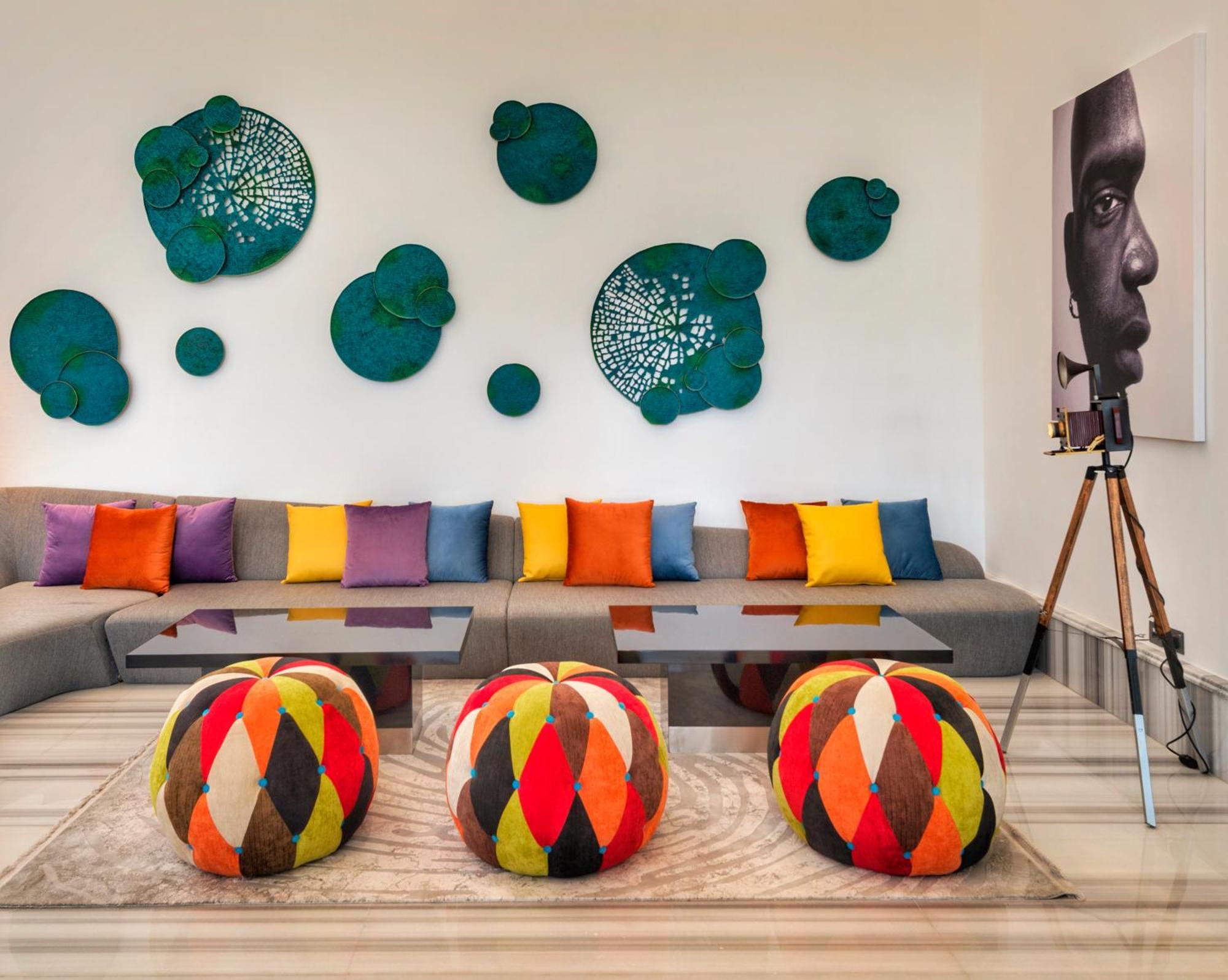 Canal Central Hotel Business Bay Dubai Exterior foto The photo shows a modern living space with a contemporary design. There is a comfortable gray sofa adorned with colorful cushions in various shades of orange, purple, and yellow. In front of the sofa, there are round ottomans or poufs with a vibrant 
